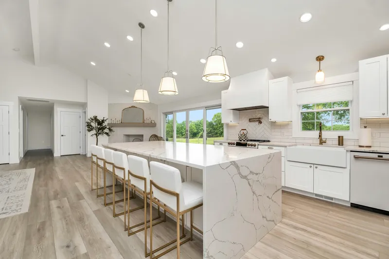 White shaker kitchen with quartz waterfall island and gold hardware