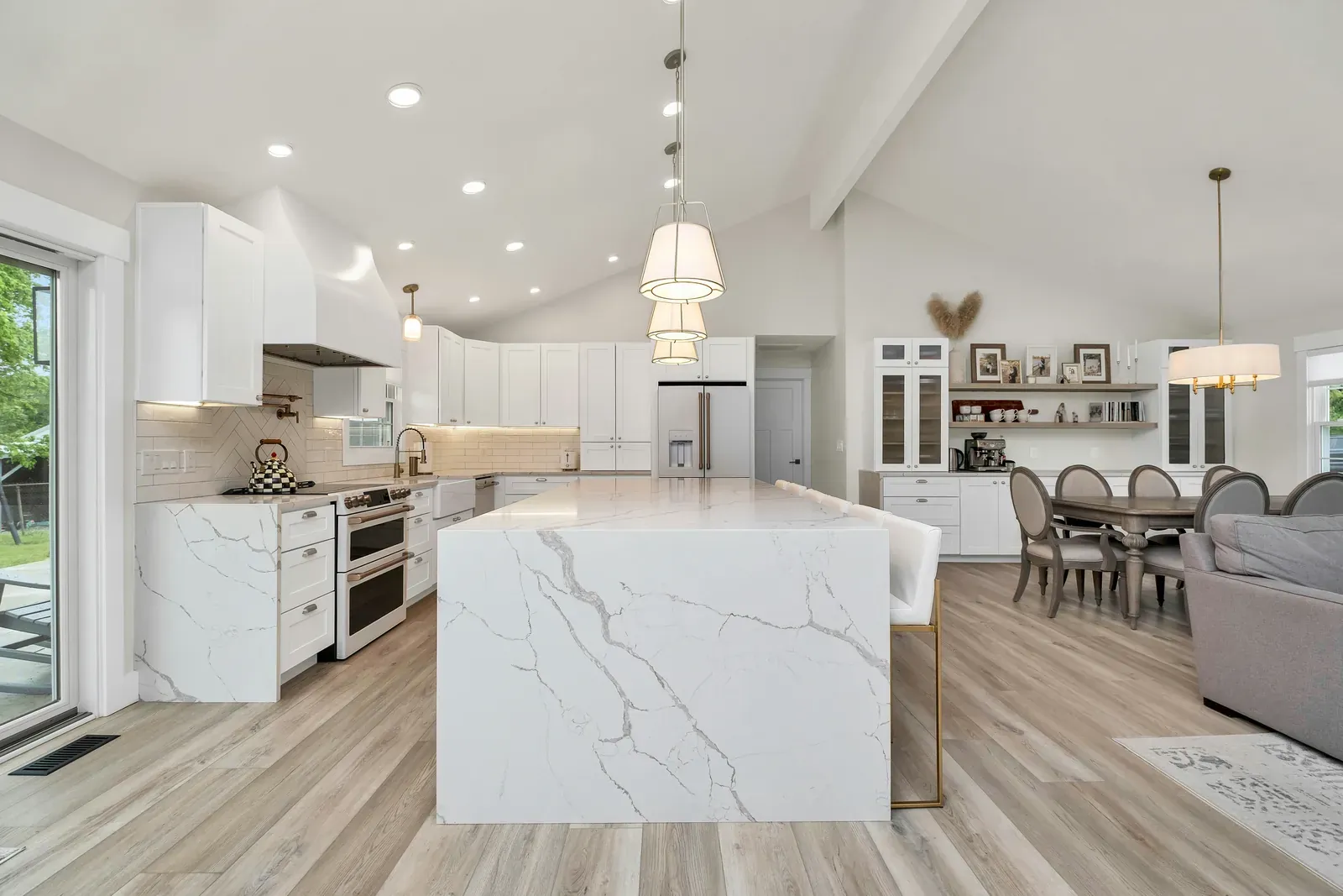 Open white kitchen with marble-look waterfall island and shaker cabinets