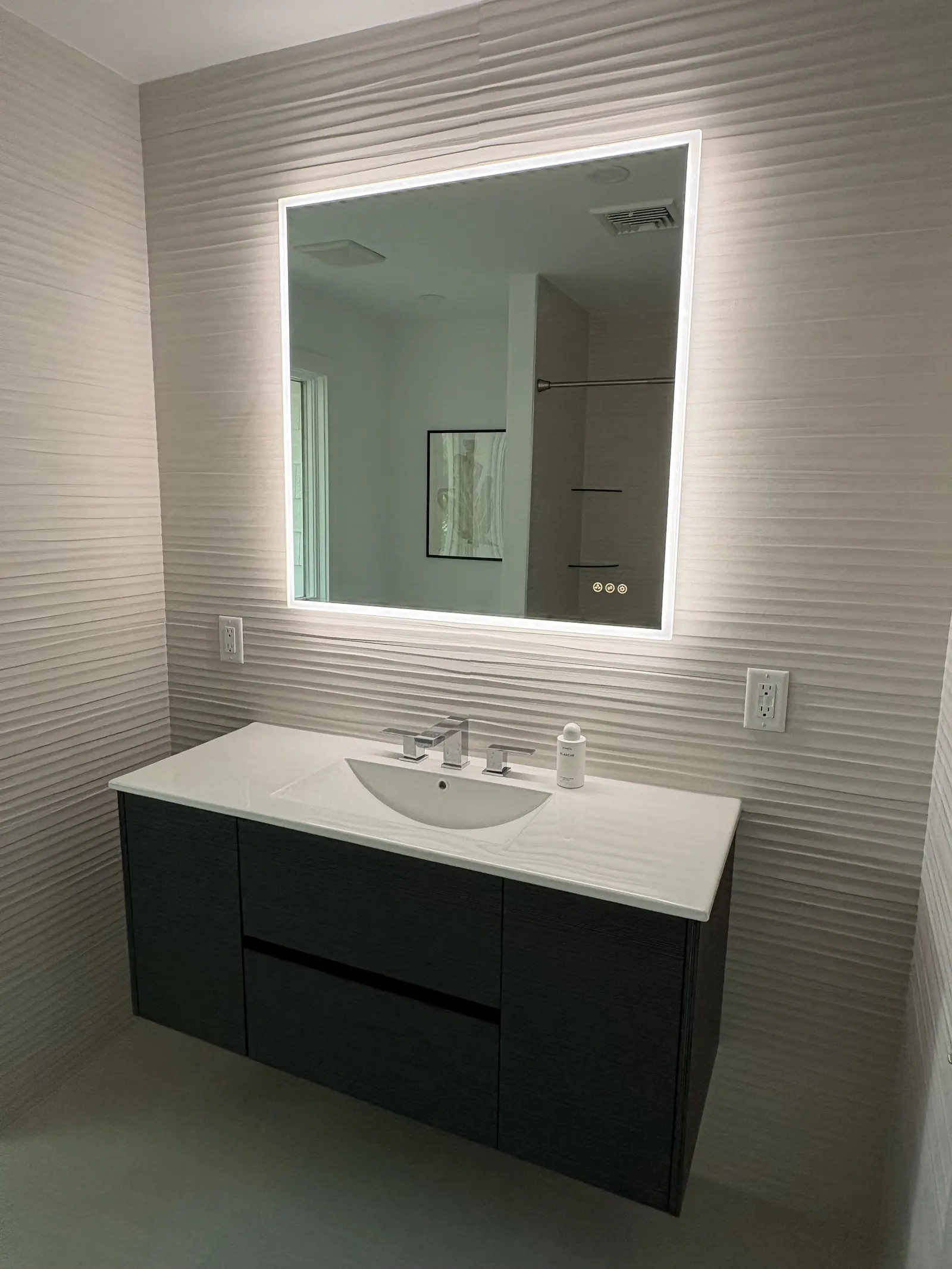 Guest bathroom with floating vanity and backlit mirror