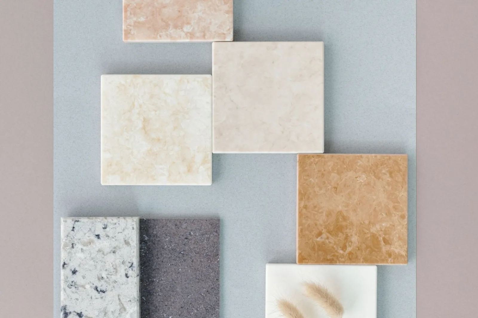 Quartz and stone countertop samples in white, cream, peach, amber and gray laid out side by side