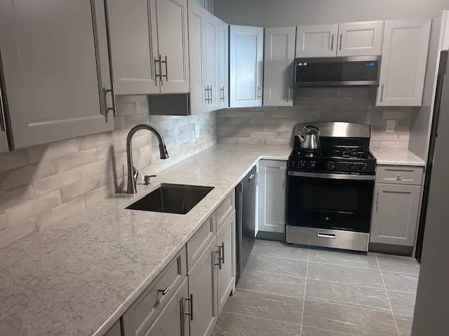 Gray shaker kitchen with stacked stone-look backsplash tile