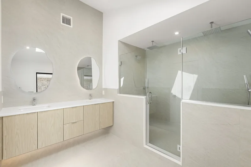 Slate-look primary bath in Cliffside Park, NJ: Large-format slate-look porcelain on walls and floor, floating oak double vanity, glass walk-in shower