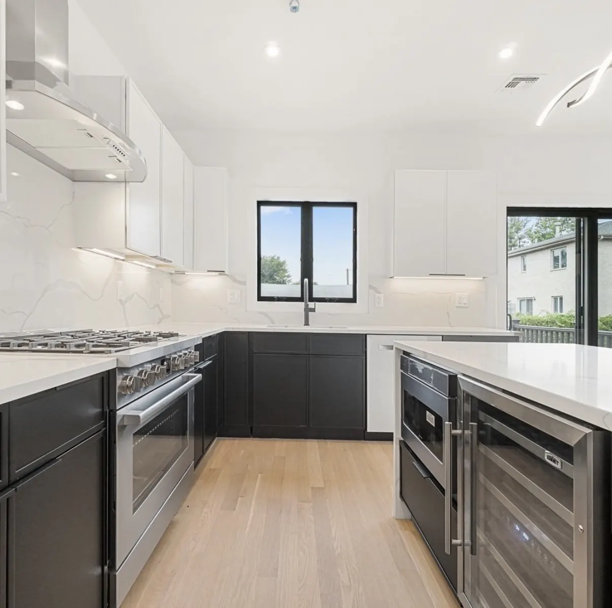 Two-tone kitchen with black base cabinets, white uppers and marble-look backsplash