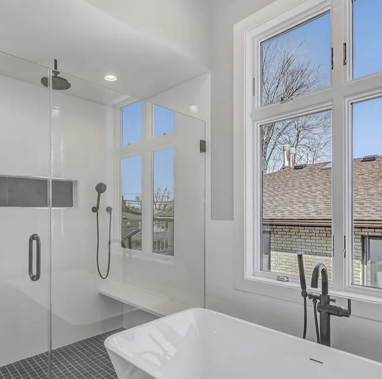 Walk-in shower and soaking tub in Edgewater, NJ: White wall tile, dark mosaic shower floor, built-in bench, freestanding tub