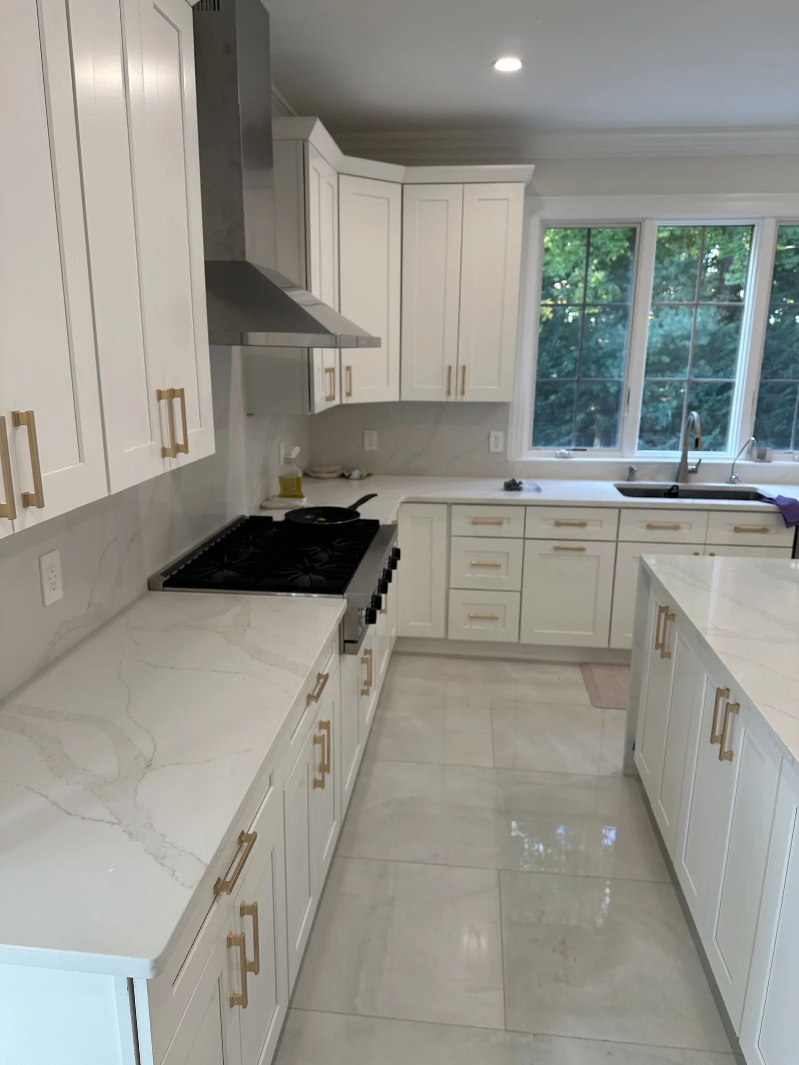 White shaker kitchen cabinets with brushed gold pulls and marble-look quartz